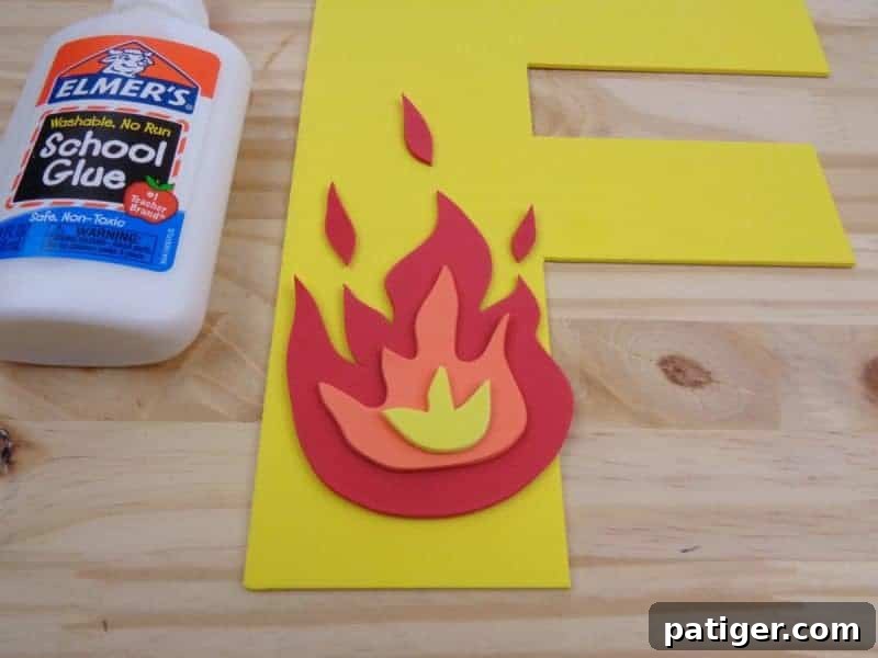 Adding teardrop shapes of red craft foam above the fire for enhanced detail and visual appeal.