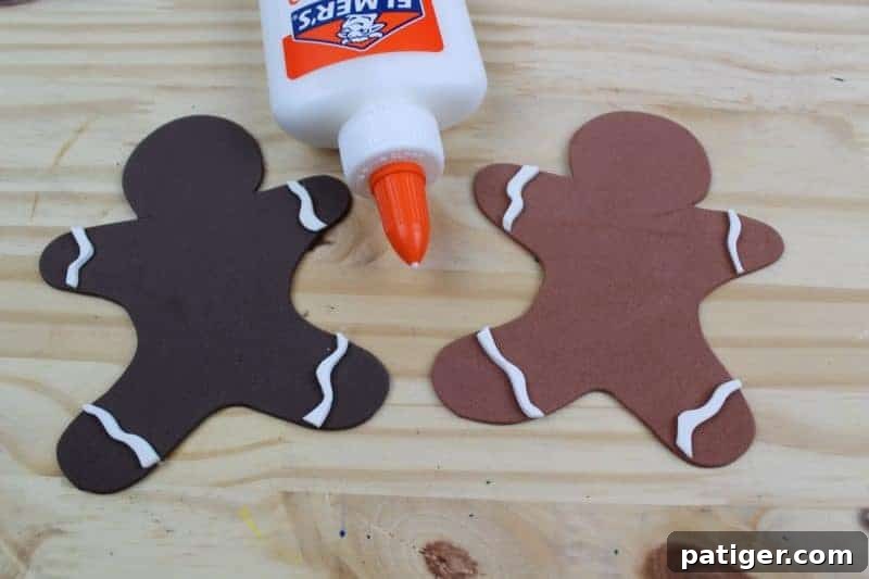 Fourth step: Gently glue the white 'icing' shapes onto the gingerbread men, carefully trimming any excess material for a clean and polished finish.
