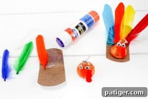 Crafting in progress: a glue stick, cut feathers, a Hershey’s Kiss with eyes and beak, and a brown paper base with a feather attached. A finished turkey craft is shown as a reference.