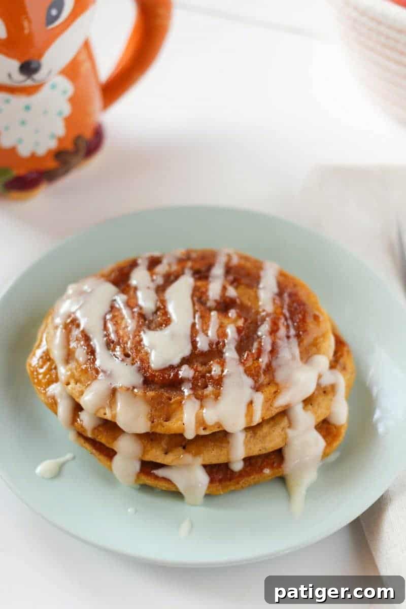 Delicious stack of cinnamon swirl pumpkin spice pancakes with cream cheese glaze