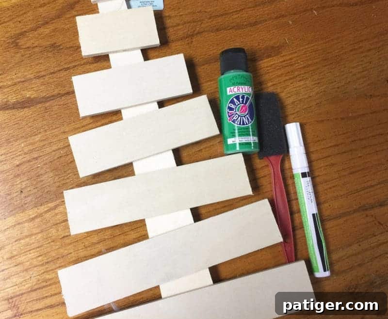 Essential supplies for a DIY wooden Christmas tree craft: blank tree, green paint, and white paint pen.