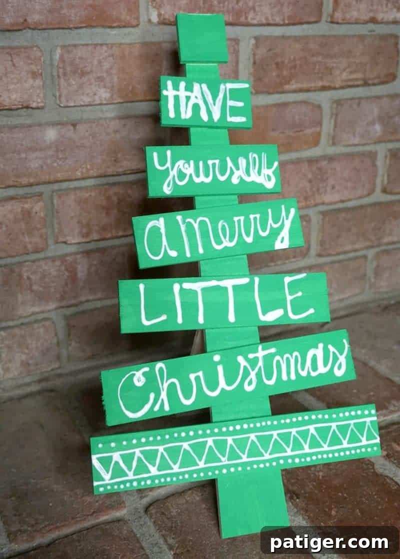 Hand-lettering a festive holiday phrase onto a painted wooden Christmas tree using a white paint pen.