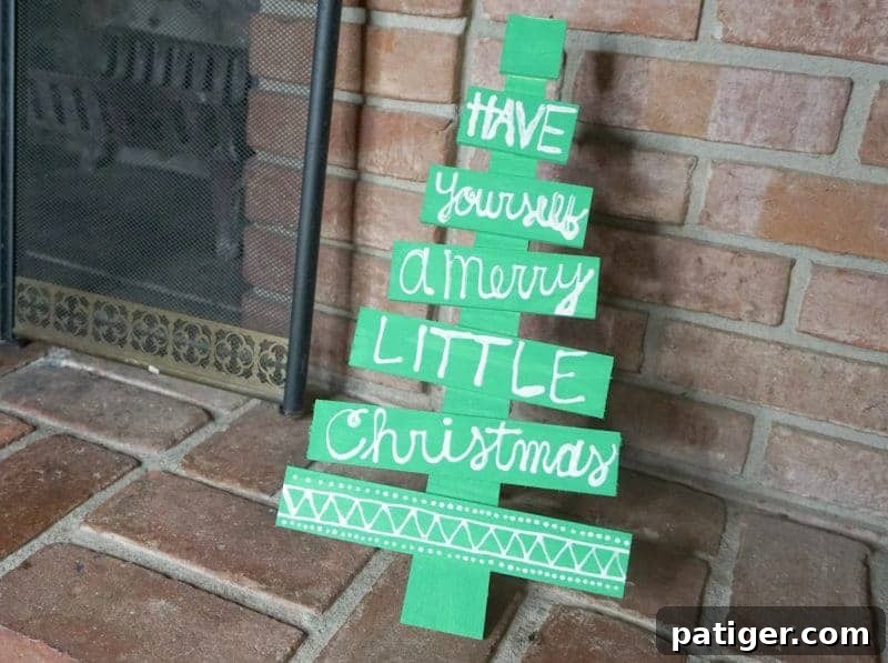 Completed DIY wooden Christmas tree with a holiday phrase and decorative elements, ready for display.