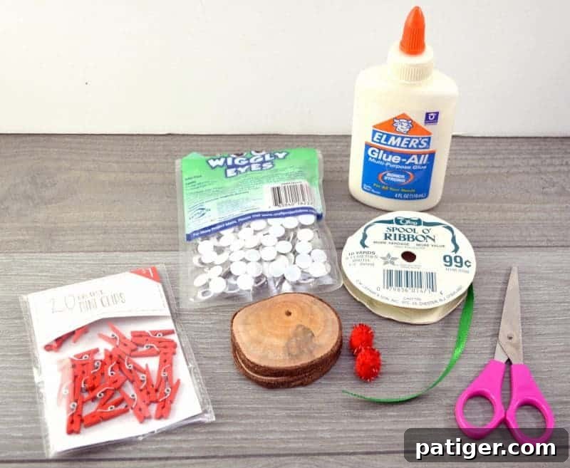 A flat lay photograph showcasing all the supplies needed for the DIY wood slice Rudolph reindeer ornament craft, including wood slices, googly eyes, red pom-poms, miniature red clothespins, ribbon, and craft glue.