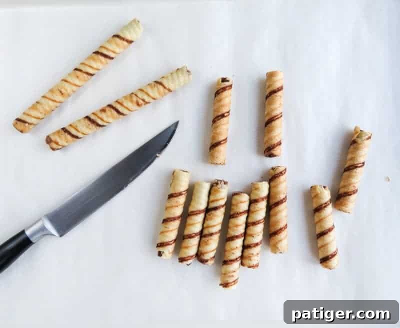Pirouline wafers cut in half and arranged on parchment paper for Christmas tree treats.