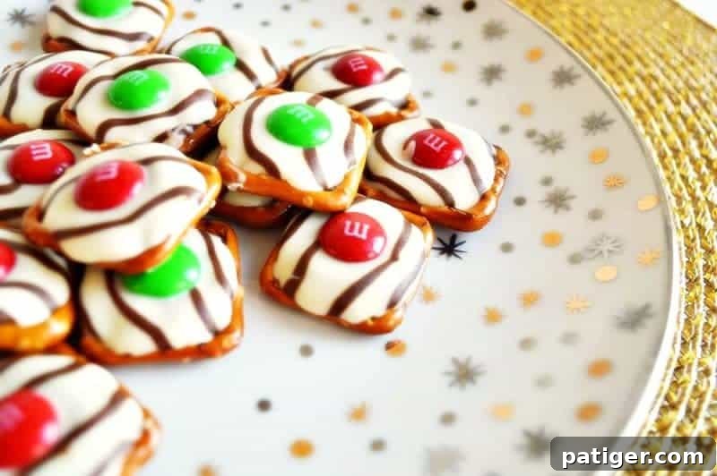 Effortless 3-Ingredient Holiday Pretzel Kisses 2 A close-up of festive Christmas pretzel hugs, showcasing square pretzels topped with melted Hershey's Hugs and colorful red and green M&Ms, ready to be served as easy holiday treats.