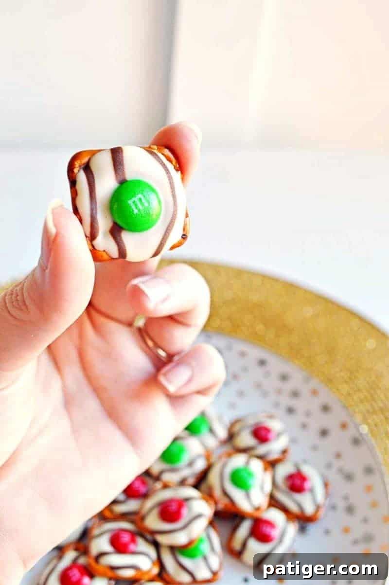 Effortless 3-Ingredient Holiday Pretzel Kisses 3 Overhead view of a tray of partially assembled Christmas pretzel hugs, showing the pretzels and Hershey's Hugs before baking, highlighting the ease of this 3-ingredient holiday snack.