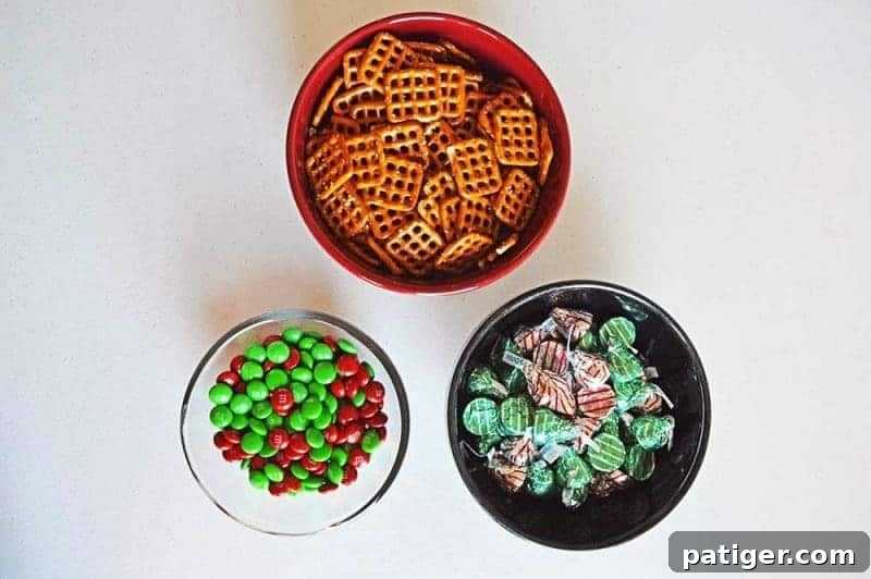 Effortless 3-Ingredient Holiday Pretzel Kisses 5 The three simple ingredients for Christmas pretzel hugs laid out: a bag of Hershey's Hugs, square pretzels, and red and green M&Ms, emphasizing the recipe's ease.