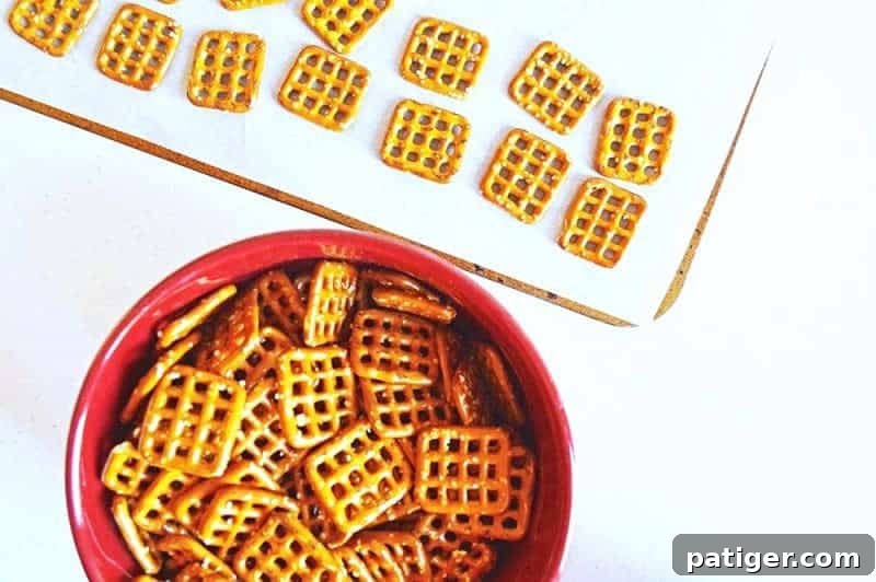 Effortless 3-Ingredient Holiday Pretzel Kisses 6 A cookie sheet lined with parchment paper, topped with square pretzels, each holding a Hershey's Hug, before going into the oven.