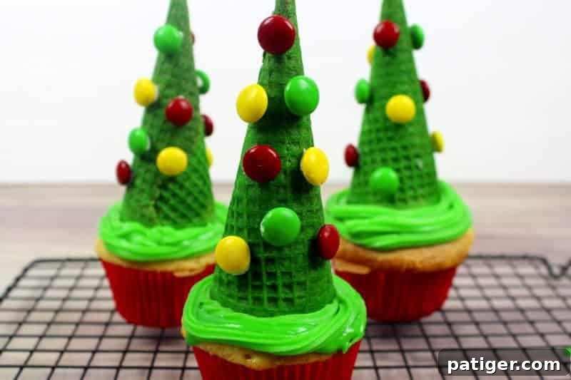 Decorating green-sprayed sugar cones with M&M's as ornaments for Christmas tree cupcakes.