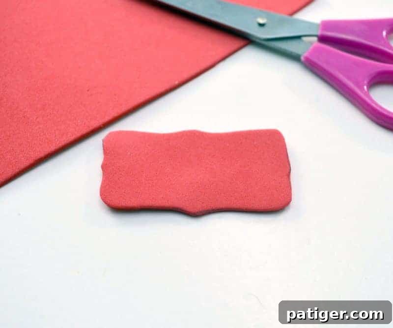 Step 1: Cutting a rectangle from red craft foam for the 'Snowball Fight' sign.