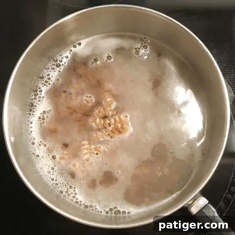 Guilt-Free Tuna Pasta Bake 6 A step-by-step image illustrating the initial mixing of the creamy sauce for the healthier tuna pasta casserole in a large bowl.