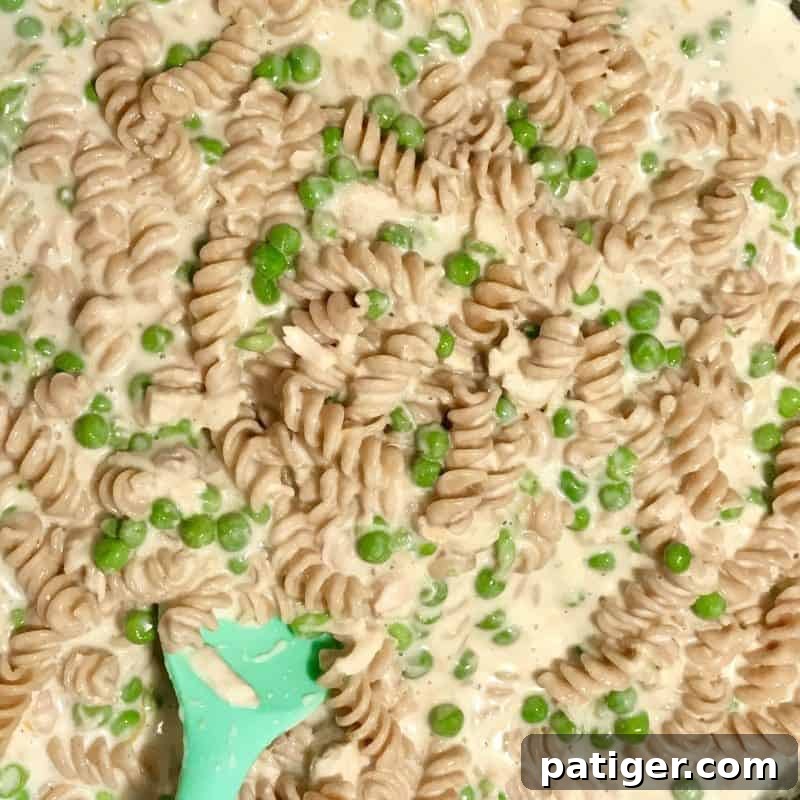 Guilt-Free Tuna Pasta Bake 7 Another instructional image showing the combined casserole mixture being transferred into a baking dish before cooking.