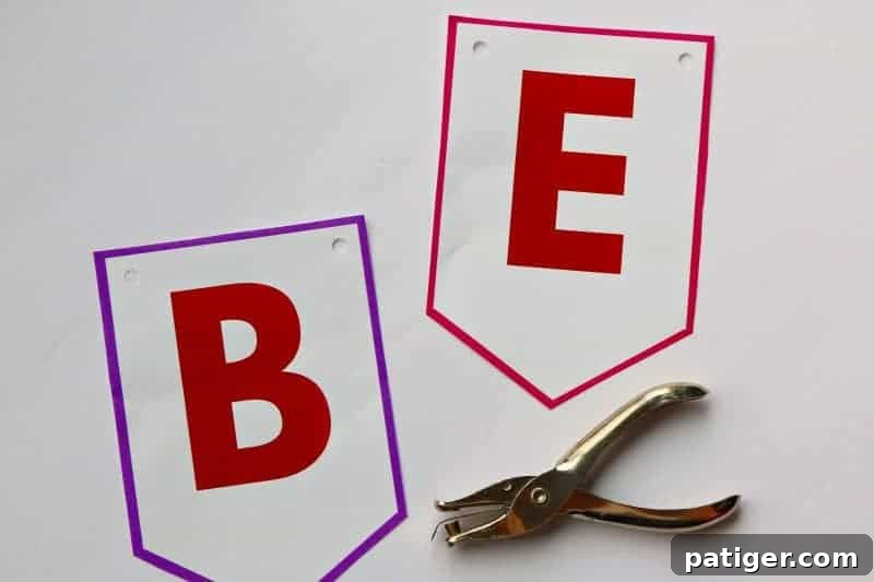 Continue your DIY Valentine decor by punching holes in the top corners of each "Be Mine" Valentine banner flag, preparing it for stringing.