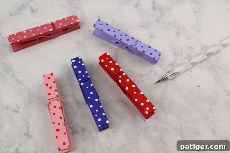Adding polka dots to a dried, painted clothespin using a stylus tool and contrasting paint