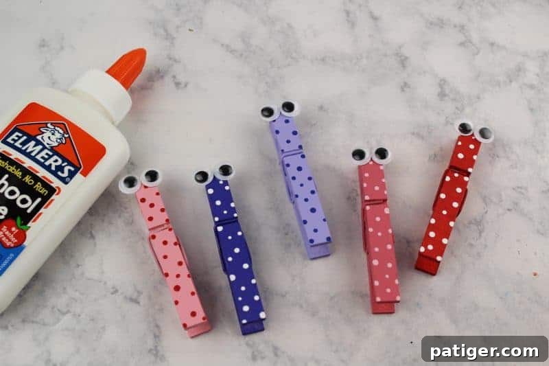 Gluing googly eyes onto the top end of a decorated clothespin, bringing the butterfly to life