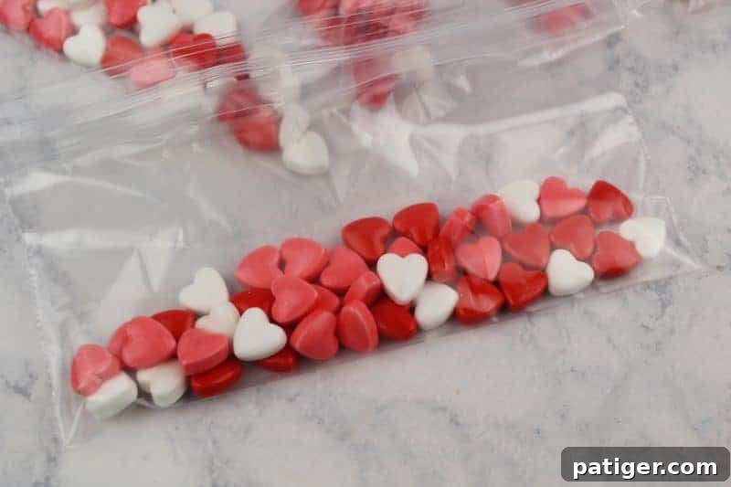Filling a snack-sized baggie with colorful candy hearts, preparing the 'wings' of the butterfly