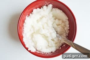 Mixing sugar scrub ingredients in a red bowl