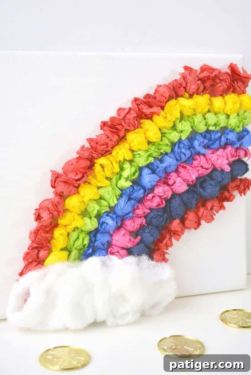 Rainbow Tissue Paper Magic 3 Close-up of a child's hand placing colorful rolled tissue paper onto a white canvas to form a rainbow, highlighting fine motor skill development.