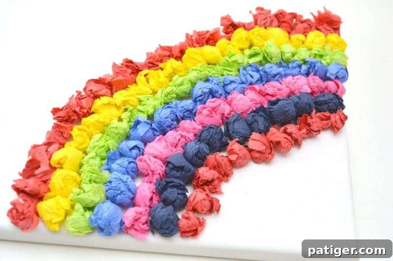 Rainbow Tissue Paper Magic 8 Rows of colorful rolled tissue paper balls meticulously placed on a canvas, forming the vibrant arcs of a rainbow craft.