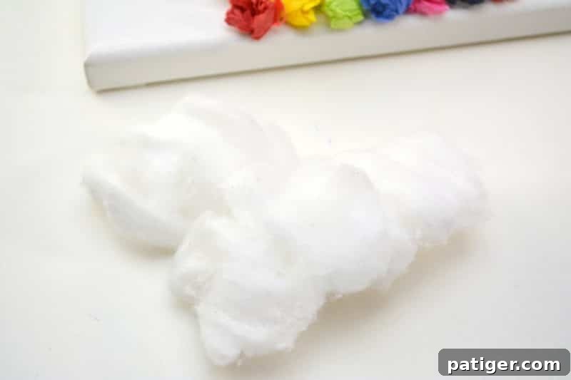 Rainbow Tissue Paper Magic 9 A child's hands gently stretching and shaping cotton balls into soft, fluffy cloud formations.