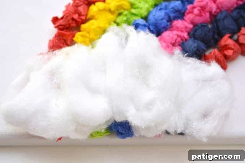 Rainbow Tissue Paper Magic 10 The finished rainbow tissue paper craft with cotton ball clouds glued at the base, displayed against a light background.