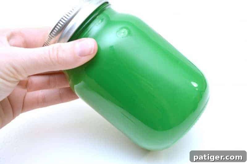 Shaking the mason jar to coat the inside with green paint