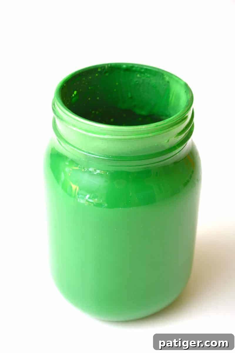 Pouring excess green paint from the mason jar