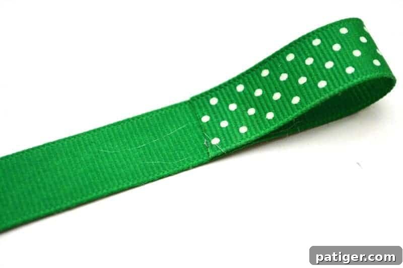 Folding one side of green ribbon towards the center to start forming a bow