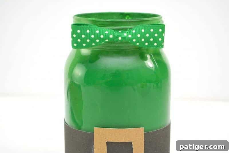 Gluing the mini bow tie to the top of the jar centered above the gold belt buckle