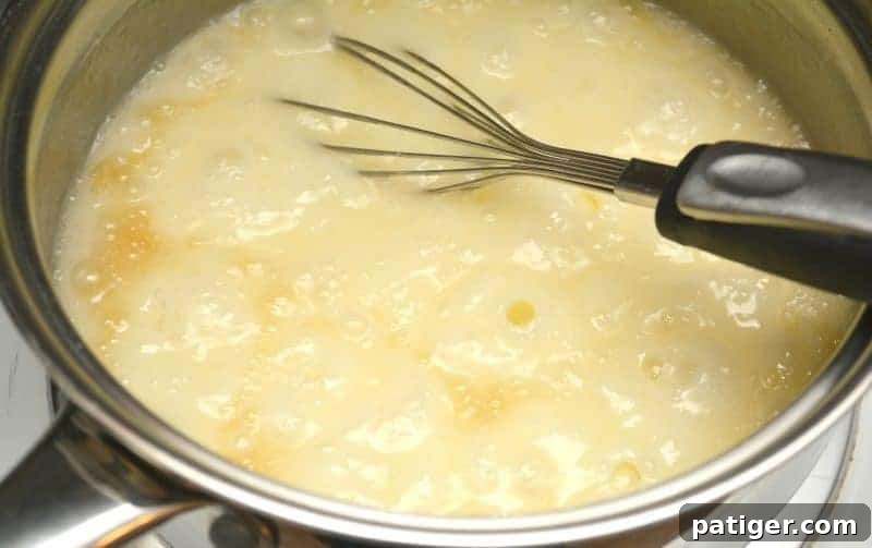 Butter, sugar, and half and half simmering in a pot, being stirred until smooth and reaching a light boil for St. Patrick's Day Green Fudge.