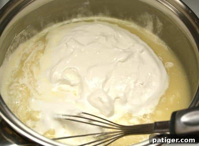 Removing the pot from heat to mix in white chocolate chips and marshmallow fluff until smooth for St. Patrick's Day Green Fudge.