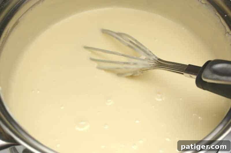 Keeping the pot with fudge mixture on low heat, stirring occasionally, to maintain warmth before coloring and layering.