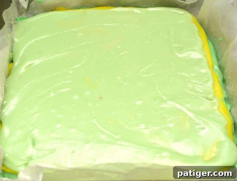 Continuing to make and layer different colored batches of St. Patrick's Day Green Fudge in the pan, ensuring each layer is spread to the edges.