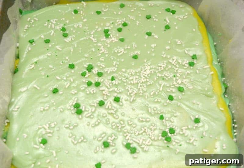 Topping off the layered green fudge with St. Patrick's Day sprinkles and gently pressing them into the surface.