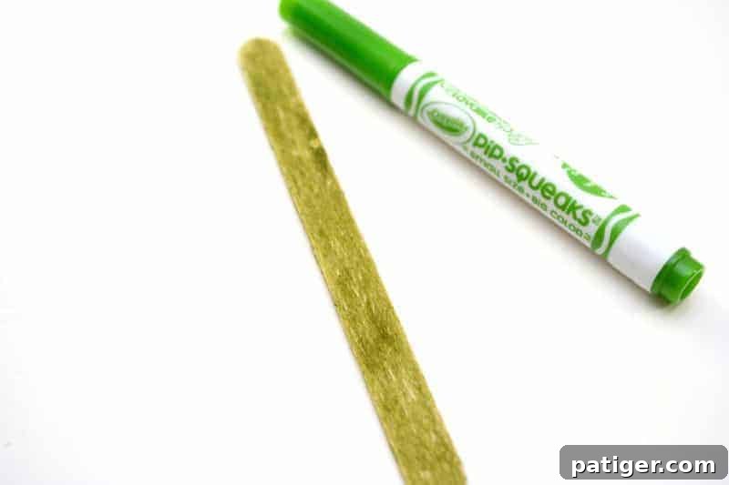 Craft a Lucky Leprechaun from Popsicle Sticks for St Patricks Day 8 Step 4: The essential step of coloring a plain popsicle stick vibrant green with a marker, preparing it to hold the leprechaun.