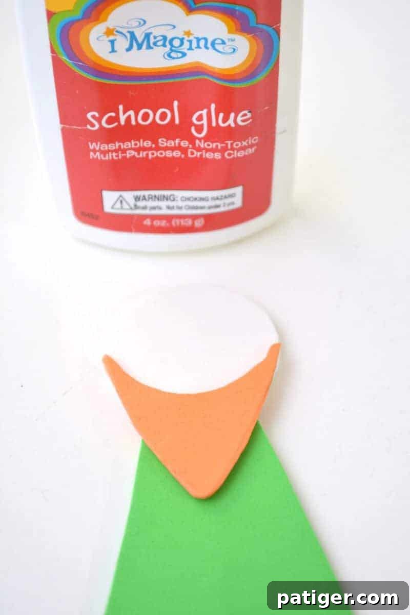 Craft a Lucky Leprechaun from Popsicle Sticks for St Patricks Day 11 Step 7: Applying glue to firmly attach the orange beard shape onto the white foam head of the leprechaun puppet.