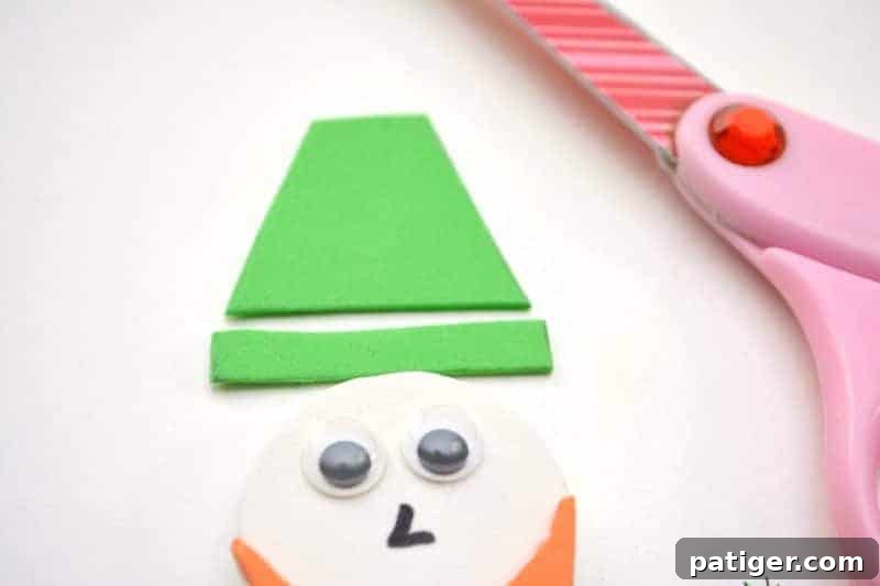 Craft a Lucky Leprechaun from Popsicle Sticks for St Patricks Day 15 Step 11: Cutting out two distinct green foam shapes - a trapezoid for the hat and a thin rectangle for the brim - to complete the leprechaun's attire.
