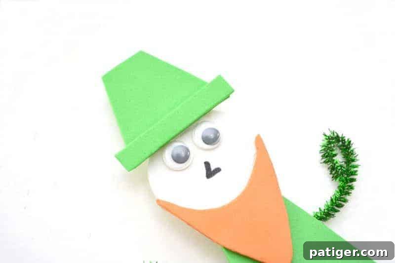 Step 12: Gently gluing the green foam trapezoid hat shape onto the top of the leprechaun's head, followed by attaching the hat's brim.