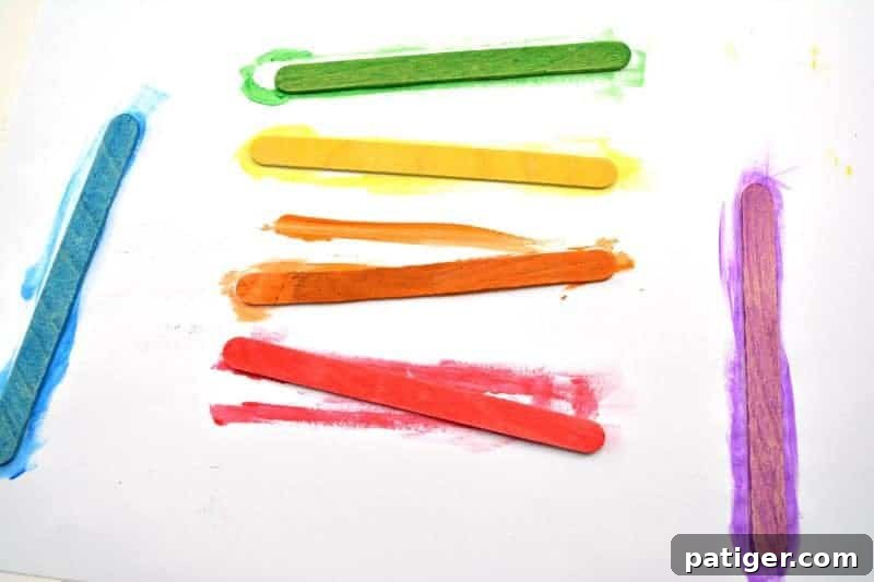 St Patricks Day Lucky Rainbow Gold Planter 4 Six popsicle sticks painted in vibrant rainbow colors: red, orange, yellow, green, blue, and purple, laid out to dry.