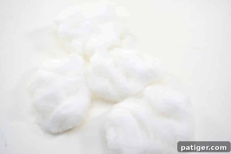 St Patricks Day Lucky Rainbow Gold Planter 8 A hand gently pulling apart cotton balls to create soft, cloud-like wisps for the craft project.