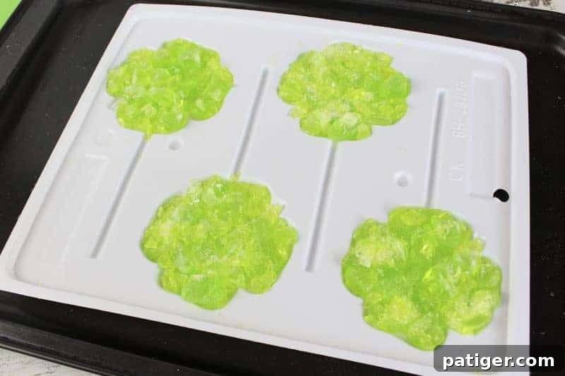 Lucky Shamrock Pops for St Patricks Day 7 Step three of making Jolly Rancher shamrock lollipops: filling the molds with crushed candy.