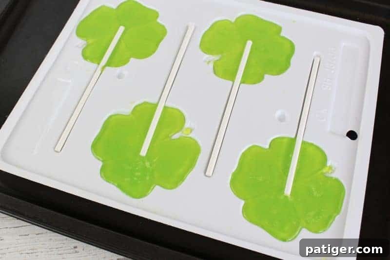 Lucky Shamrock Pops for St Patricks Day 8 Step four of making Jolly Rancher shamrock lollipops: inserting sticks into melted candy.