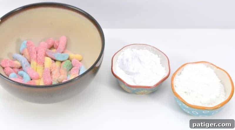 Ingredients for edible silly putty: sour gummy worms, cornstarch, and powdered sugar, laid out for an easy DIY craft.
