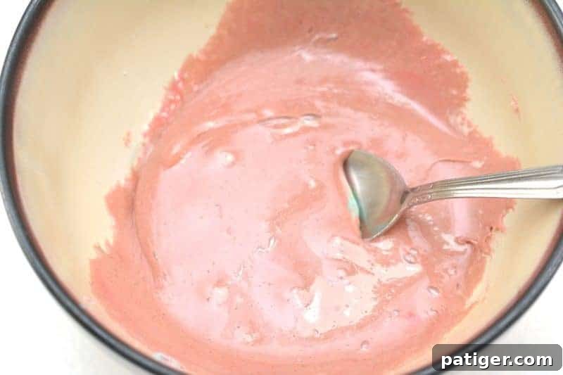 Stirring melted gummy worms to blend colors, a crucial step in creating vibrant edible silly putty.