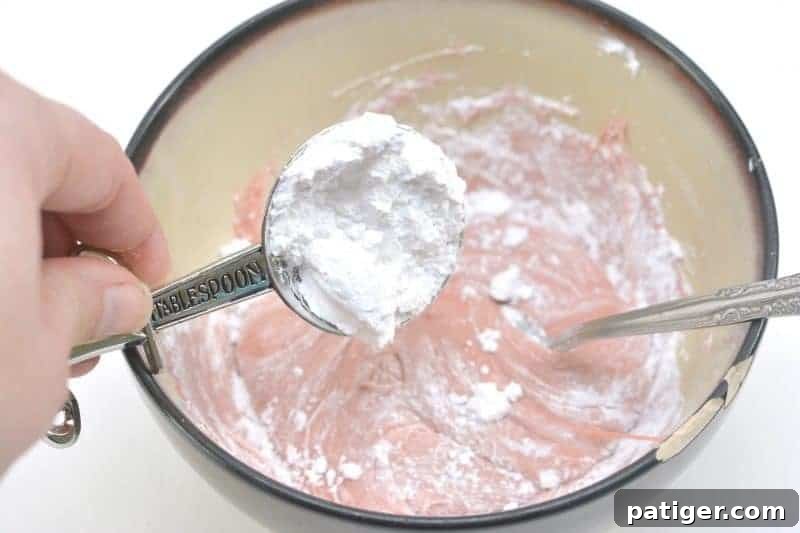 Mixing powdered sugar into the gummy worm and cornstarch mixture for smooth, edible silly putty.