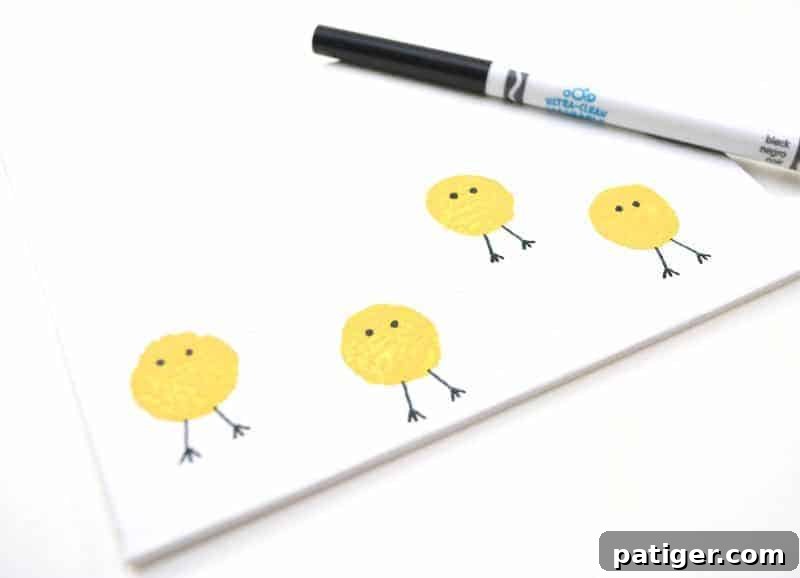 Close-up of a yellow cork-stamped chick body on a canvas, with drawn black eyes and legs, ready for its beak.