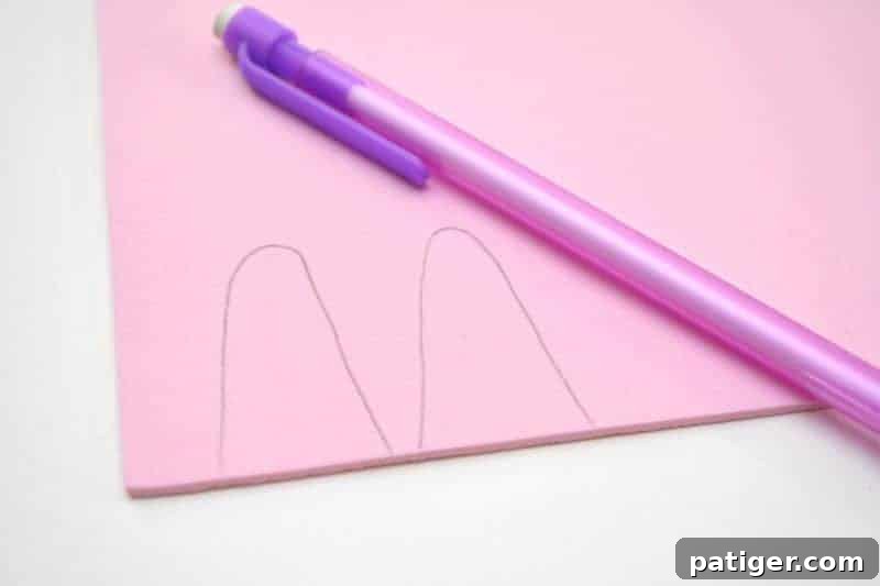 The initial step in crafting Easter Bunny Pudding Cups: drawing the distinct ear shapes on a piece of pink craft foam, demonstrating clarity and ease.