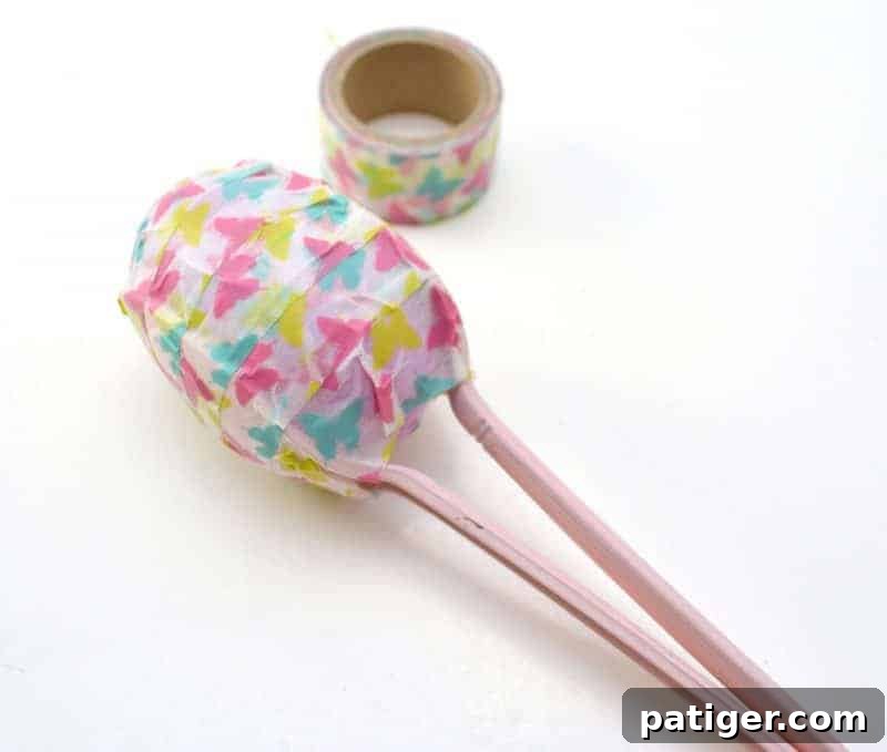 Two plastic spoons positioned around a sealed Easter egg, ready to be secured with washi tape to form a maraca.