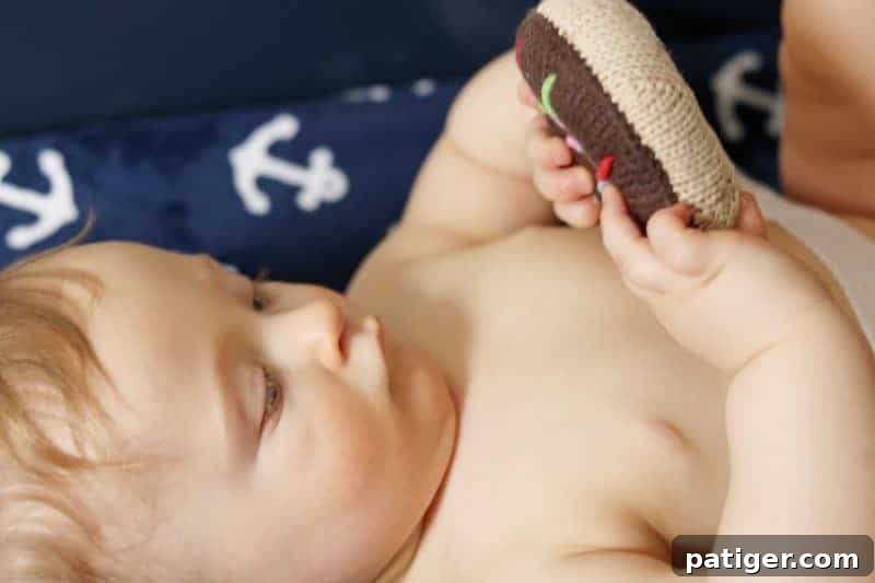 Create the Perfect Diaper Changing Station 8 Baby playing with a donut rattle on a changing table, demonstrating the use of distractions during diaper changes.